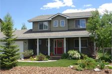 Large Green Home with Small Trees and Plants in Front